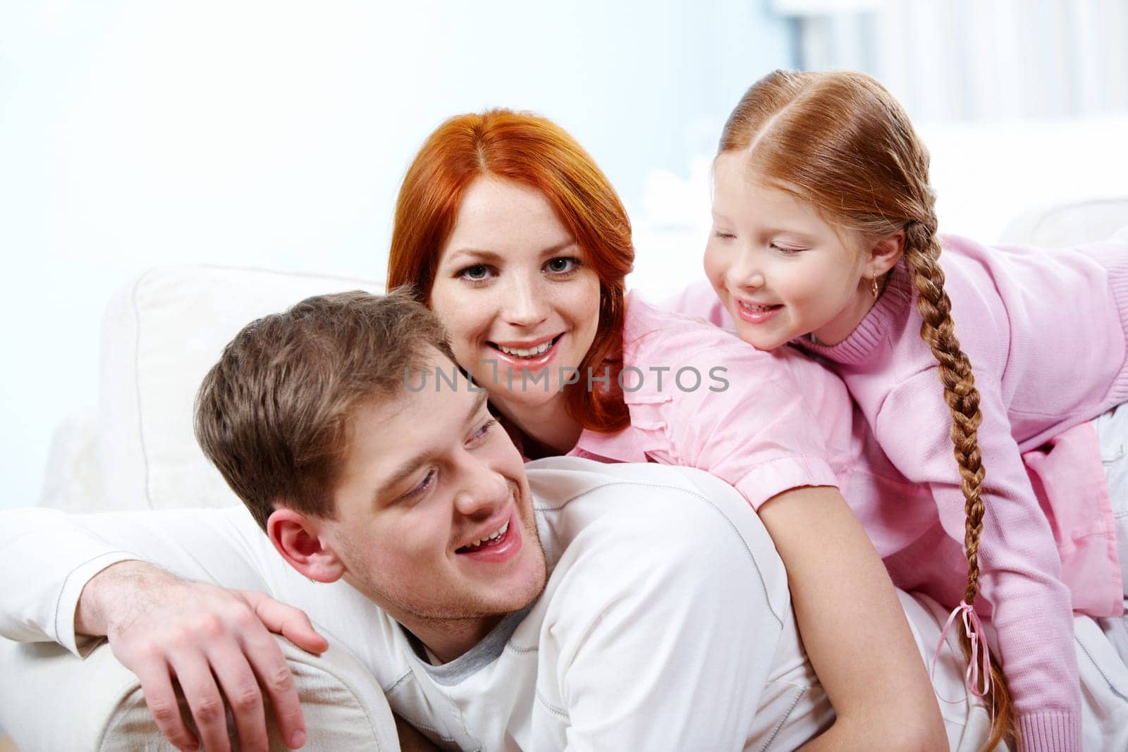 Portrait of happy parents and their daughter having fun at home