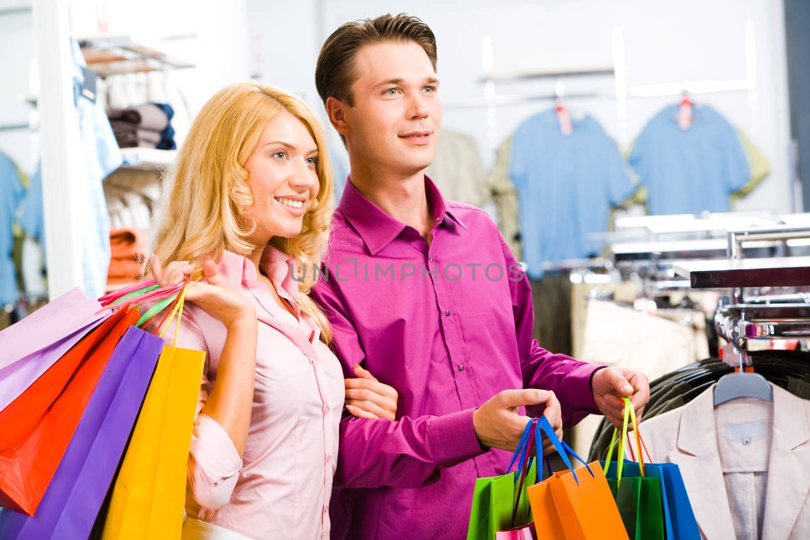 Portrait of modern couple with shopping bags looking at clothes in the trade center