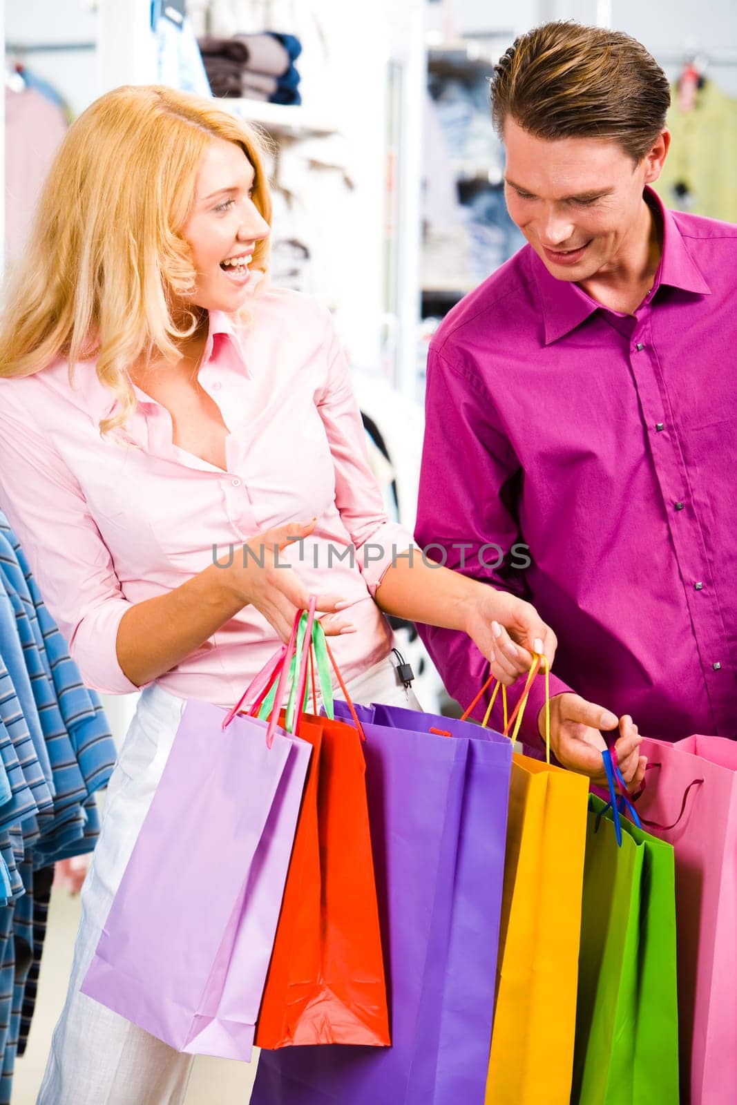Portrait of cheerful woman showing presents to her boyfriend in the store