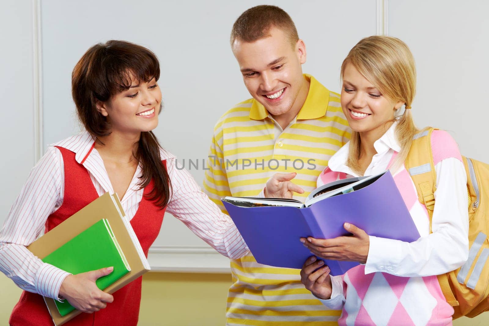 Portrait of three friends standing in classroom and discussing lessons