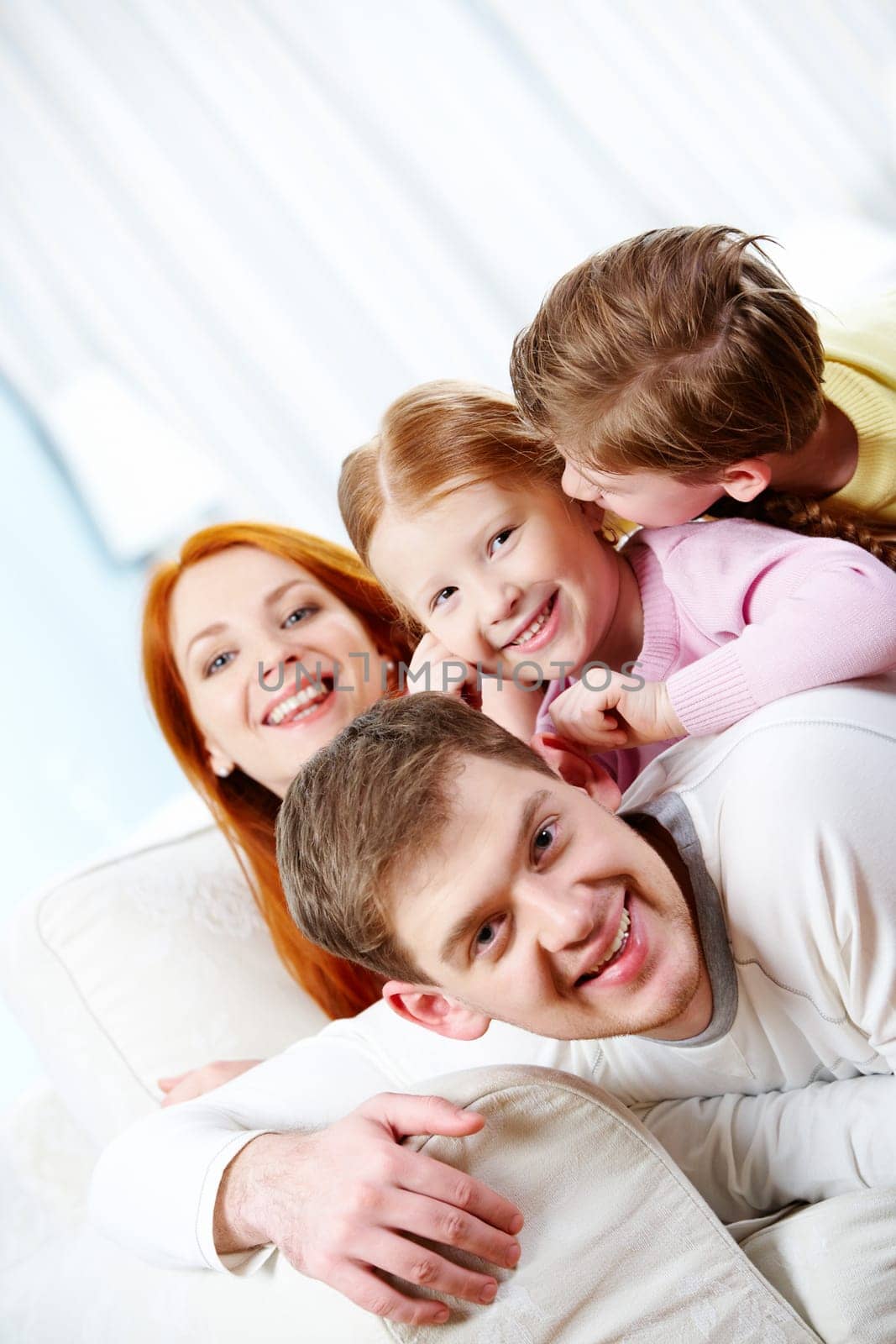 Portrait of happy parents and their children lying on the sofa