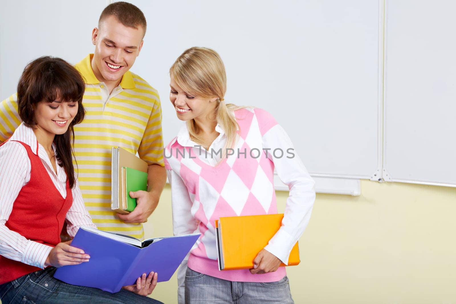 Portrait of smart students looking at textbook in girls hands and reading it