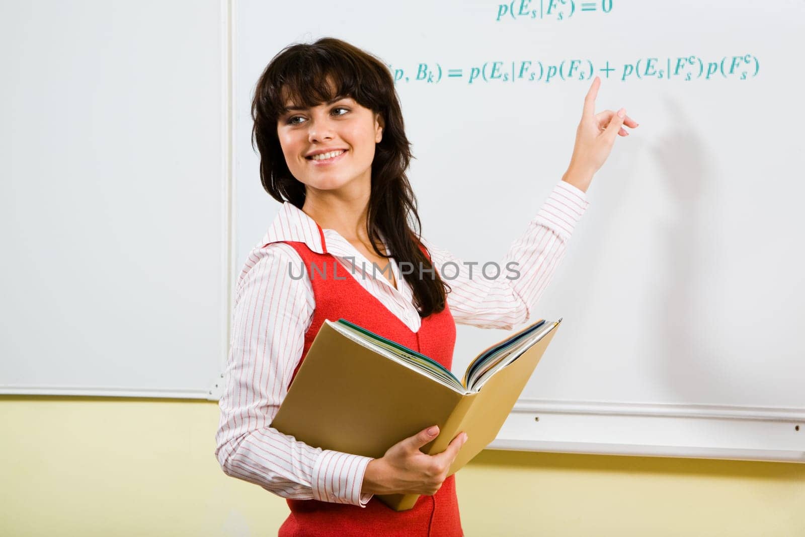 Portrait of clever girl standing near whiteboard and pointing at algebraic formula on it