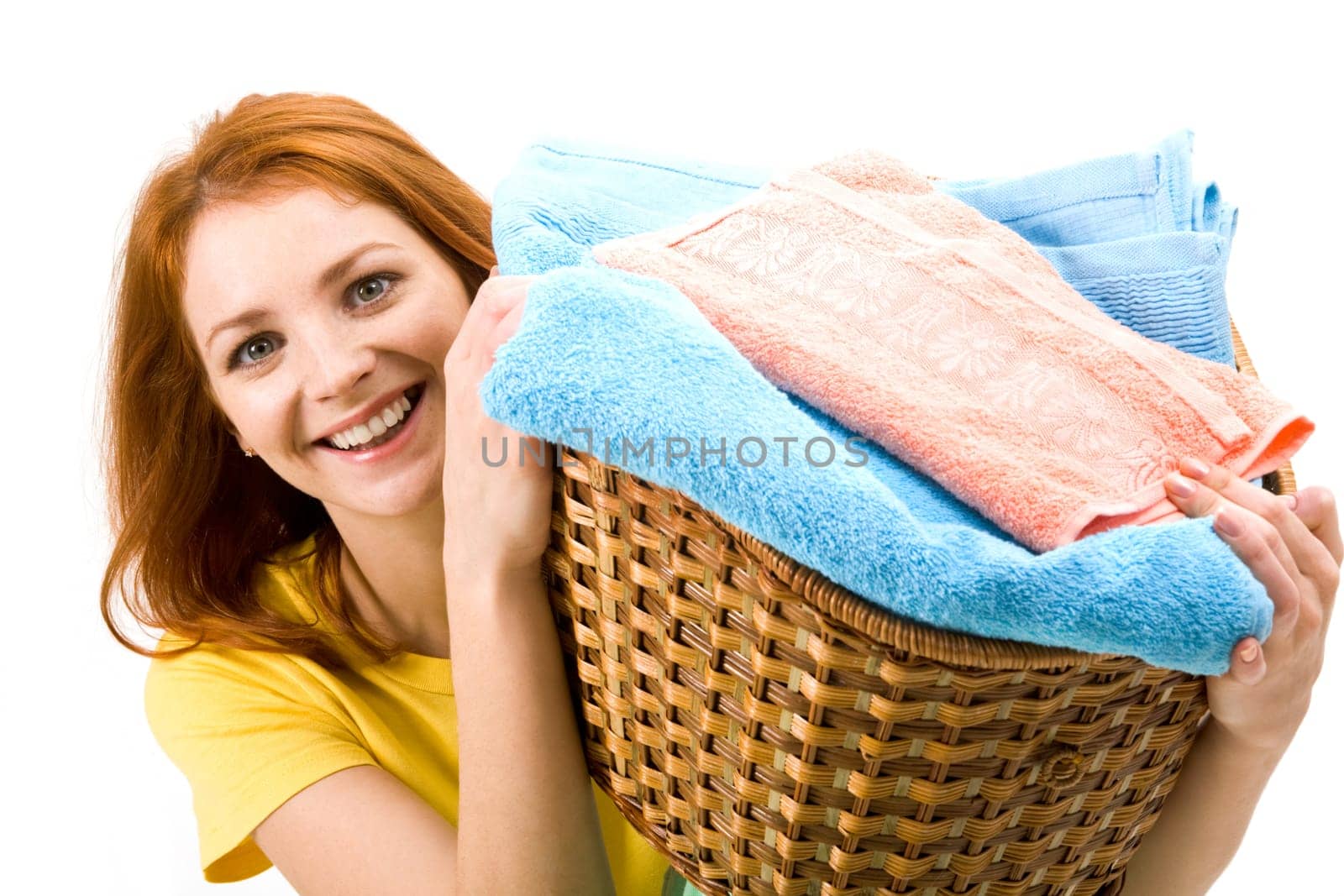 Portrait of young female holding basket full of colorful towels and smiling to camera