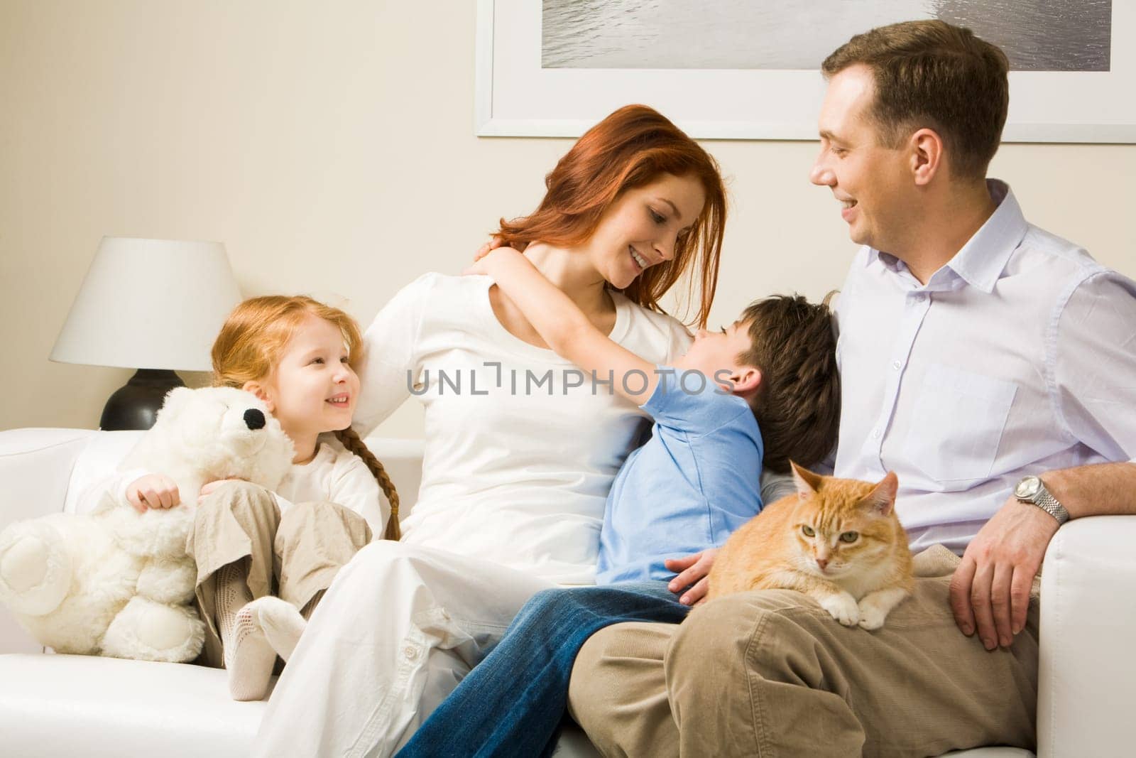 Photo of cute boy embracing his pretty mother surrounded by playful daughter and their father