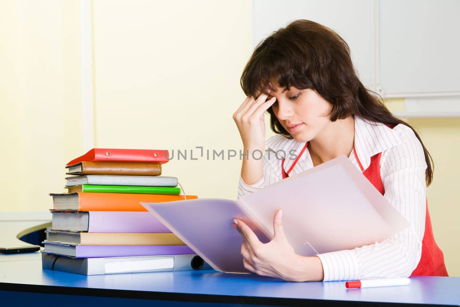 Photo of pensive teacher sitting at the desk and refreshing study material before lesson