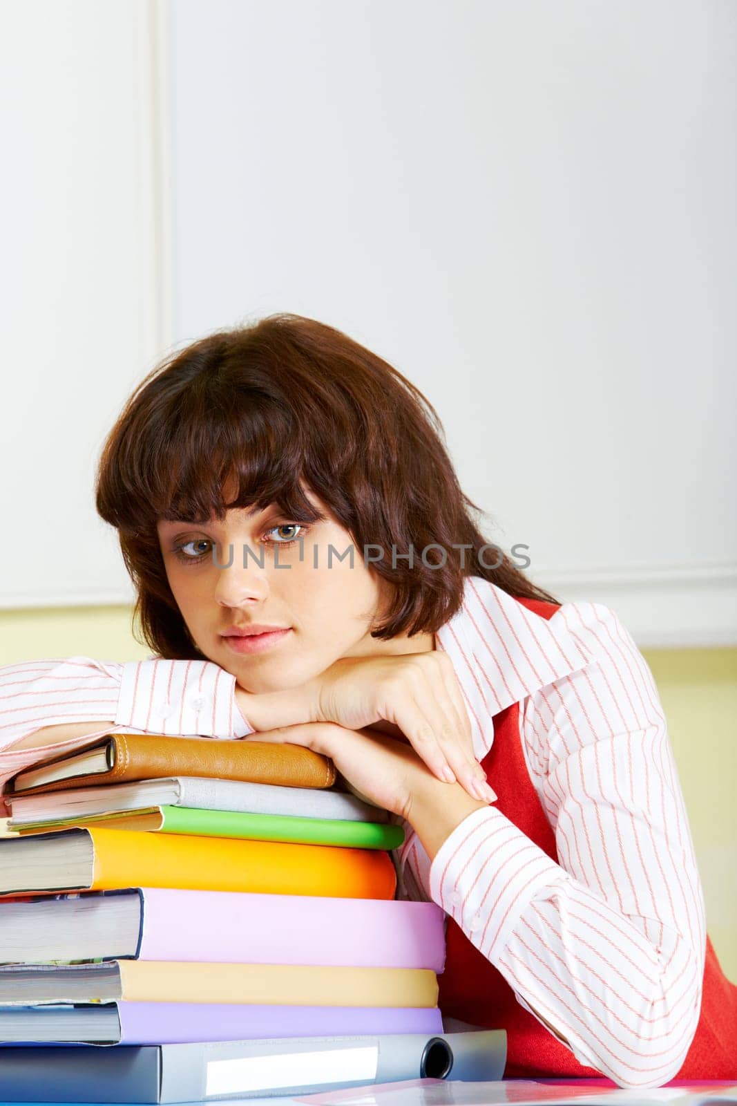 Photo of attractive woman putting her head onto stack of books and looking aside