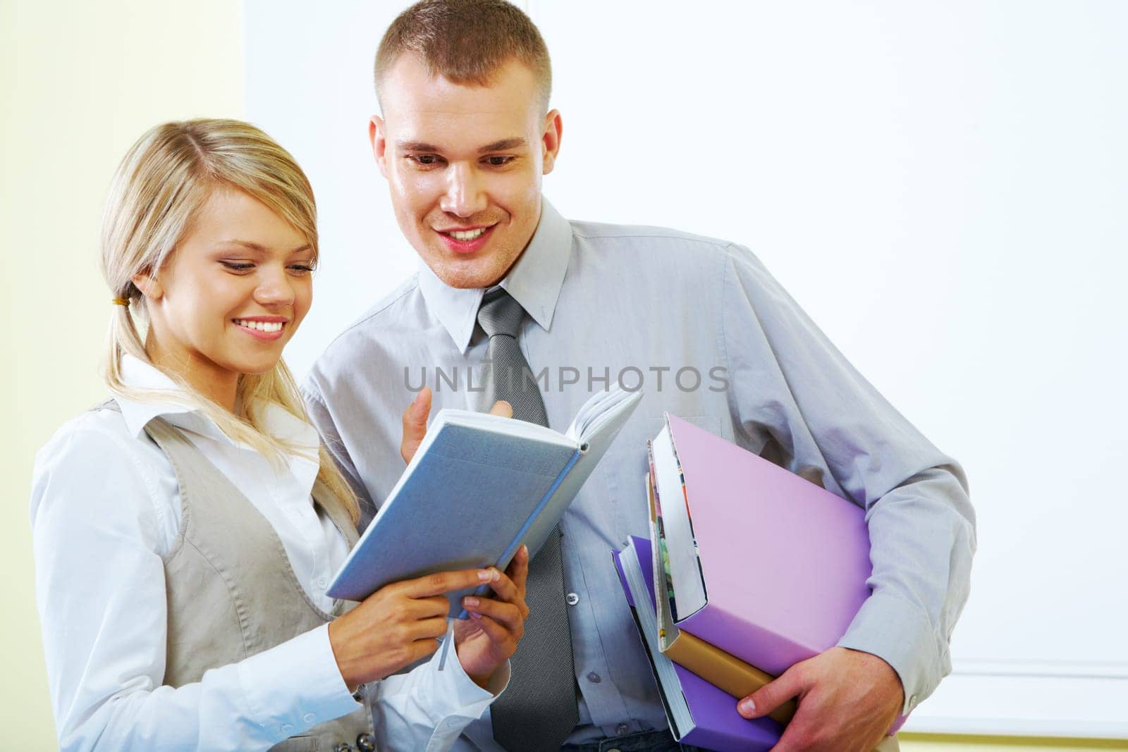 Portrait of two successful students looking into notebook together with smiles