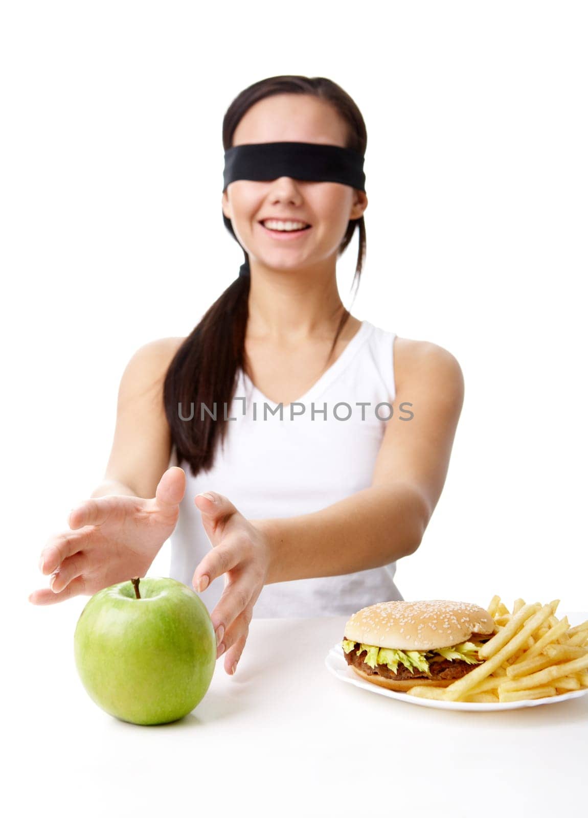 Portrait of young girl with her eyes folded deciding what to eat: an apple or fast food