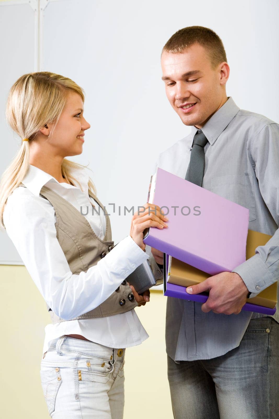 Portrait of smart girl watching at her boyfriend and taking his book in classroom