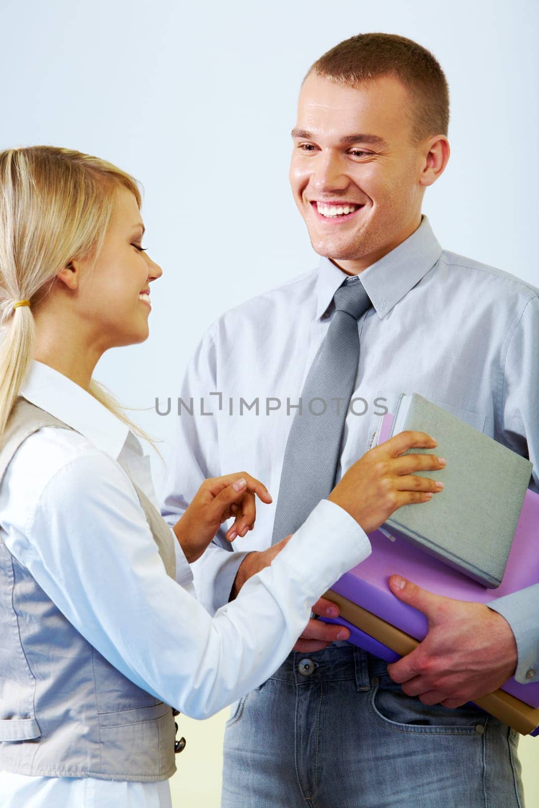 Portrait of smart girl watching at her boyfriend and taking his book in classroom