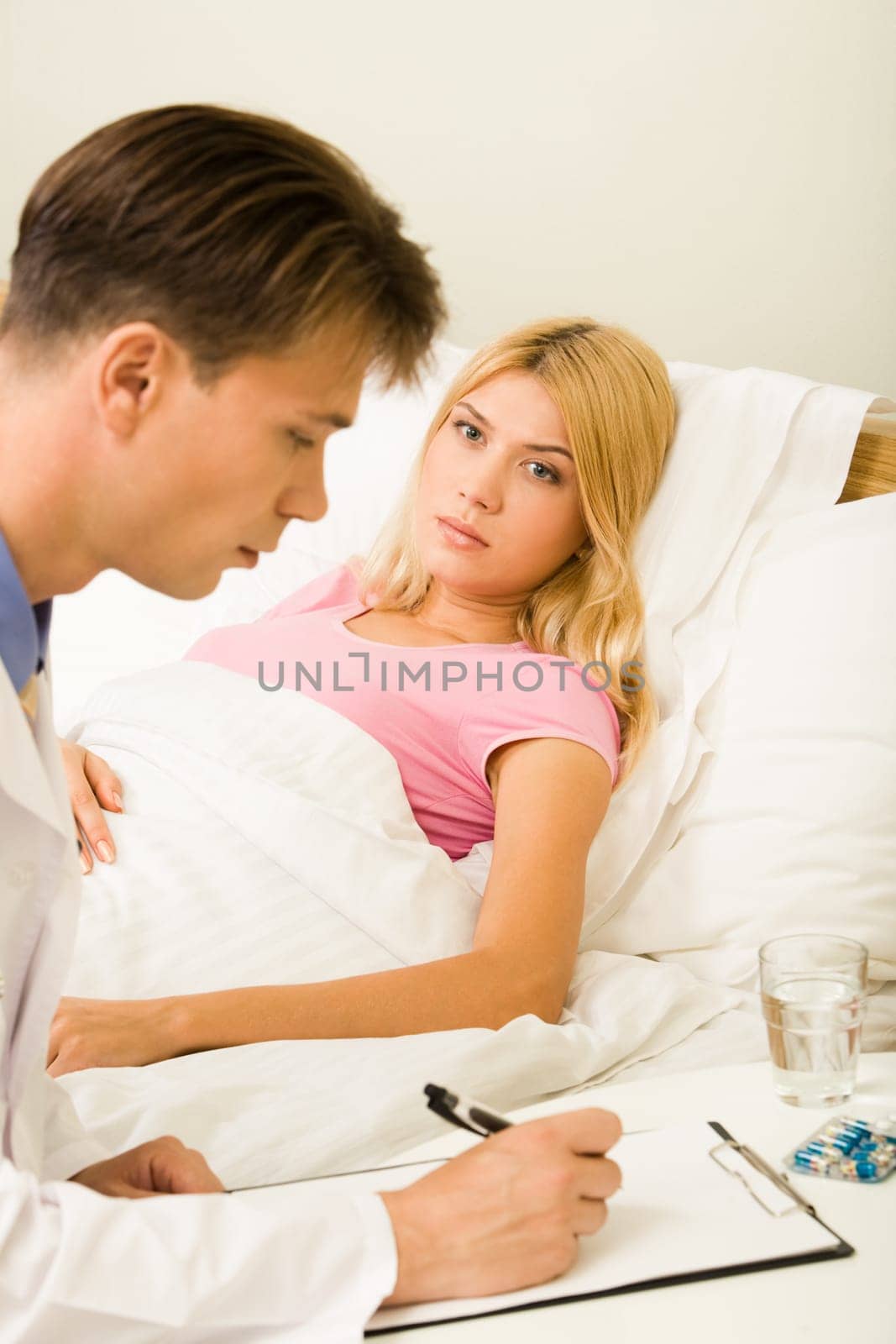 Vertical image of practitioner prescribing medication to a young ill woman in bed
