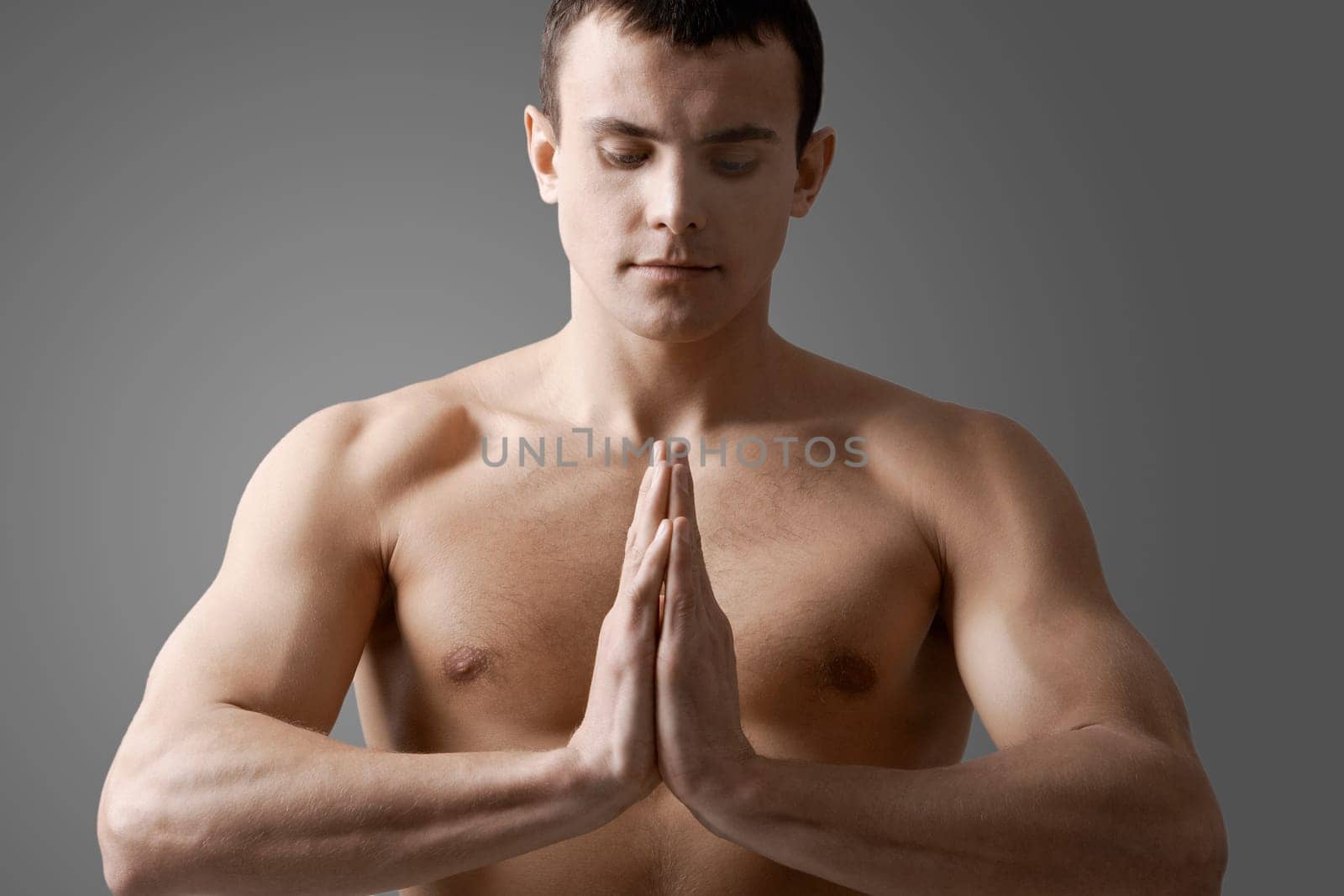 Image of handsome man with bare torso meditating