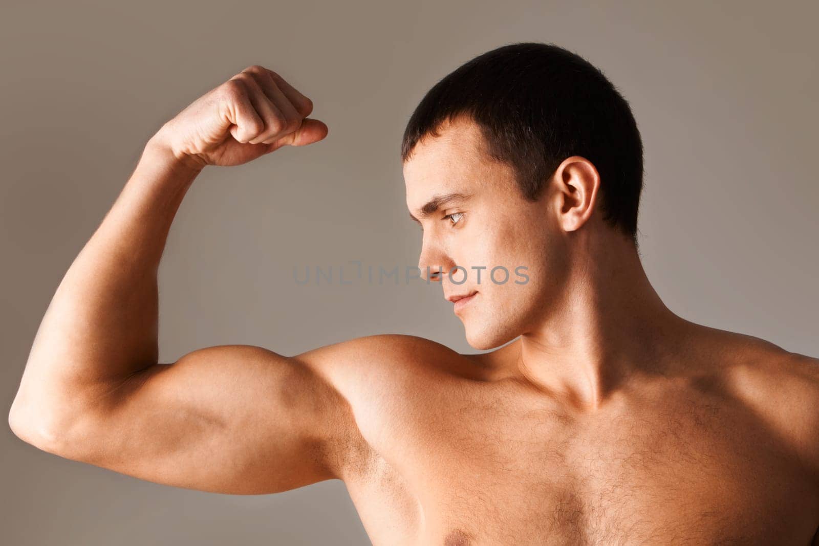 Image of powerful man looking at his muscles during exercise