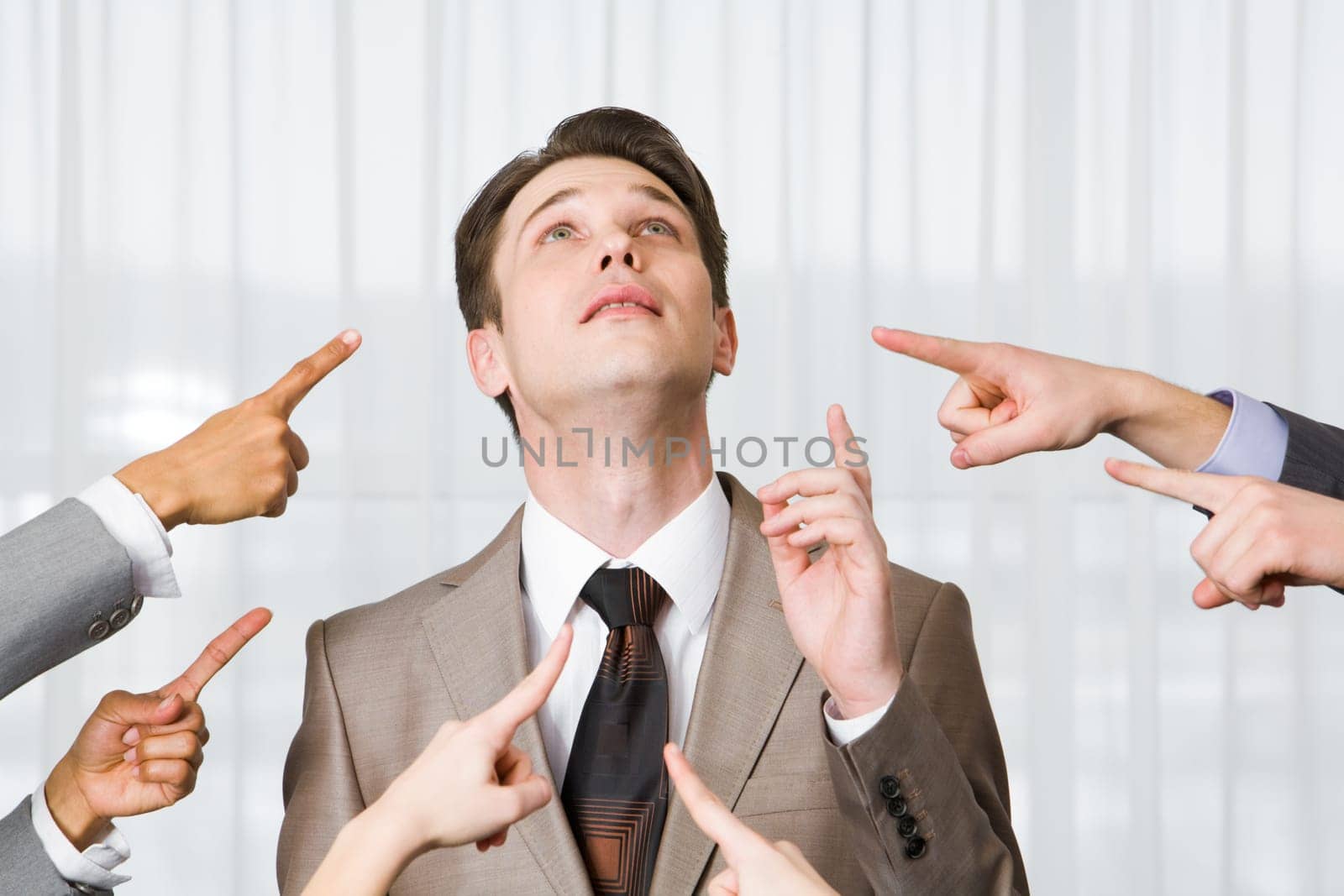 Inquiring businessman pointing upwards surrounded by several forefingers