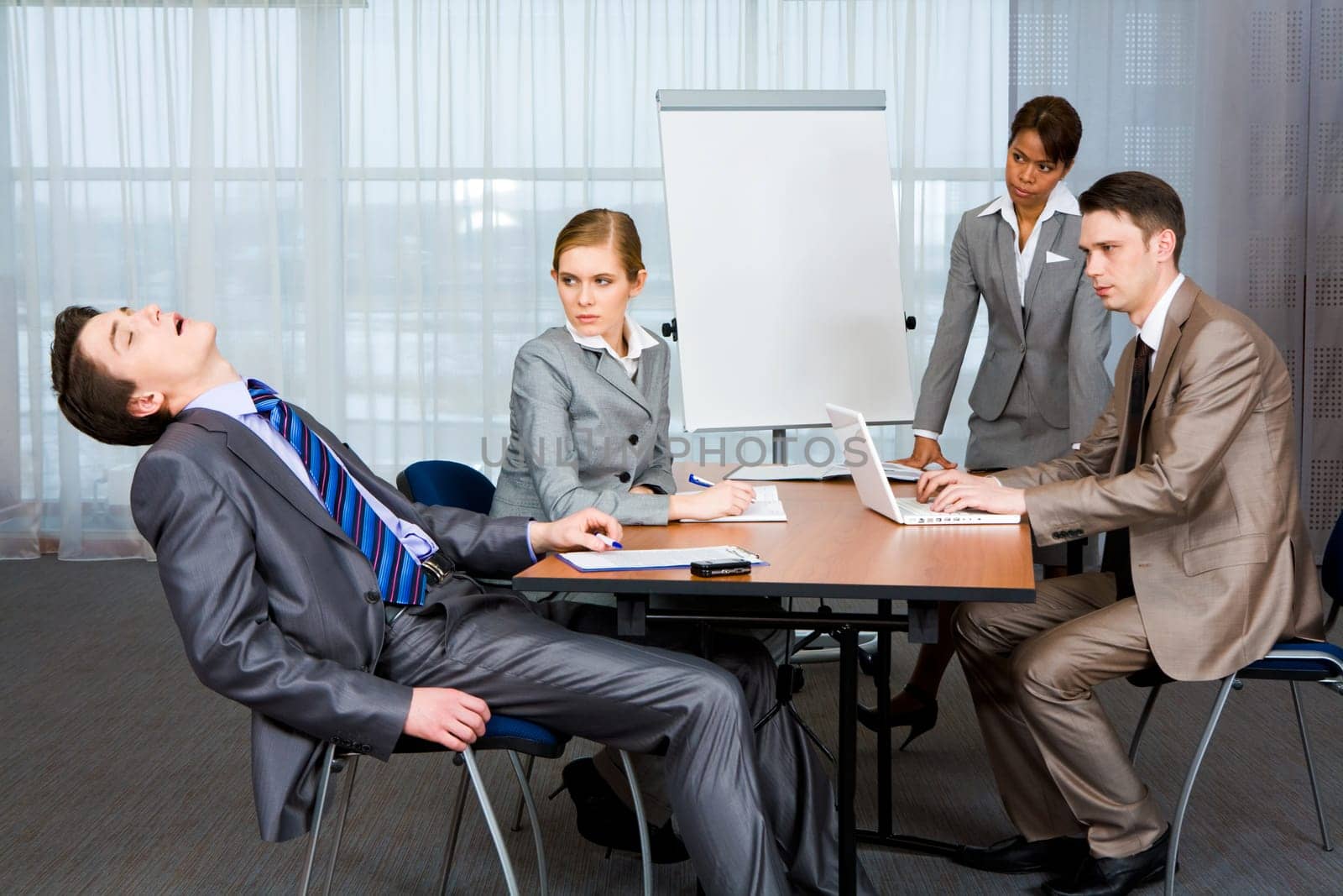 Photo of displeased businesspeople looking sternly at snoring man at presentation