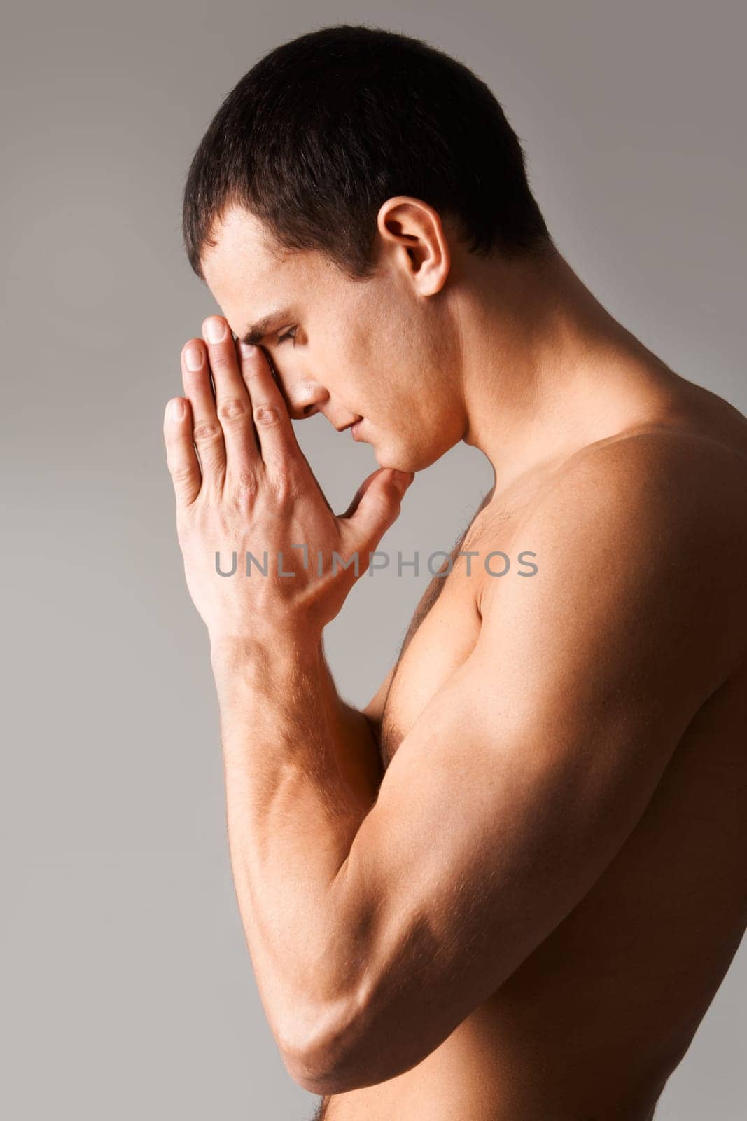 Image of shirtless man keeping his hands by face while thinking