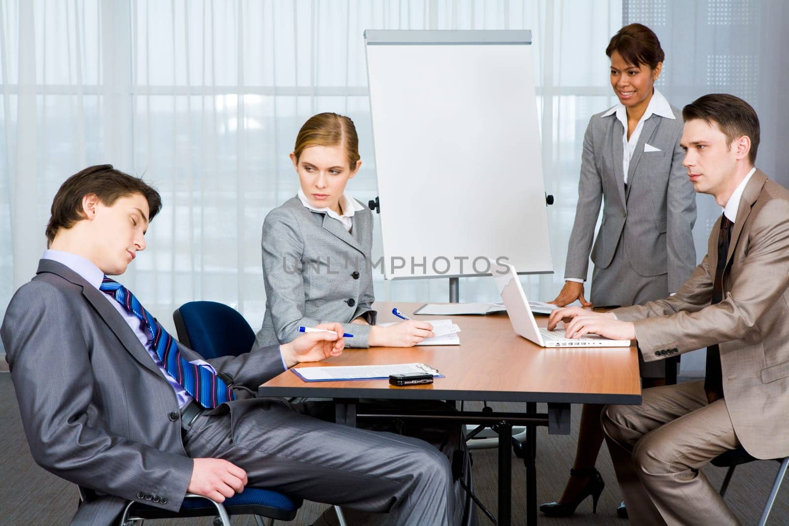 Photo of businesspeople looking sternly at their sleeping colleague at presentation