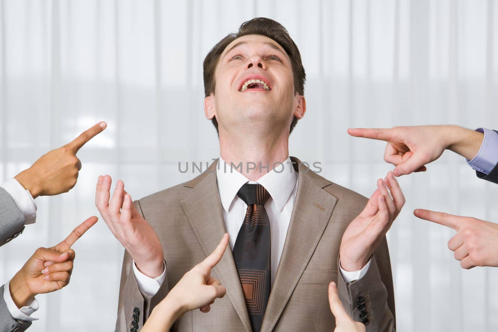 Inquiring businessman looking upwards surrounded by pointing hands