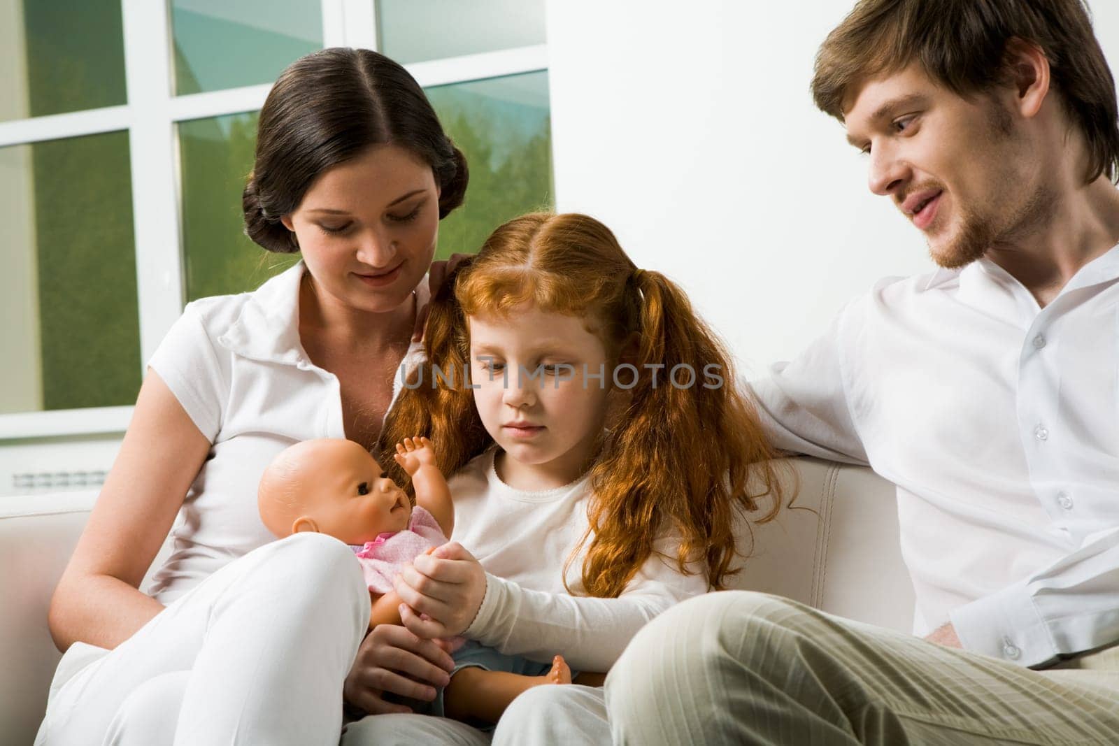 Portrait of affectionate parents and their daughter sitting on sofa at home