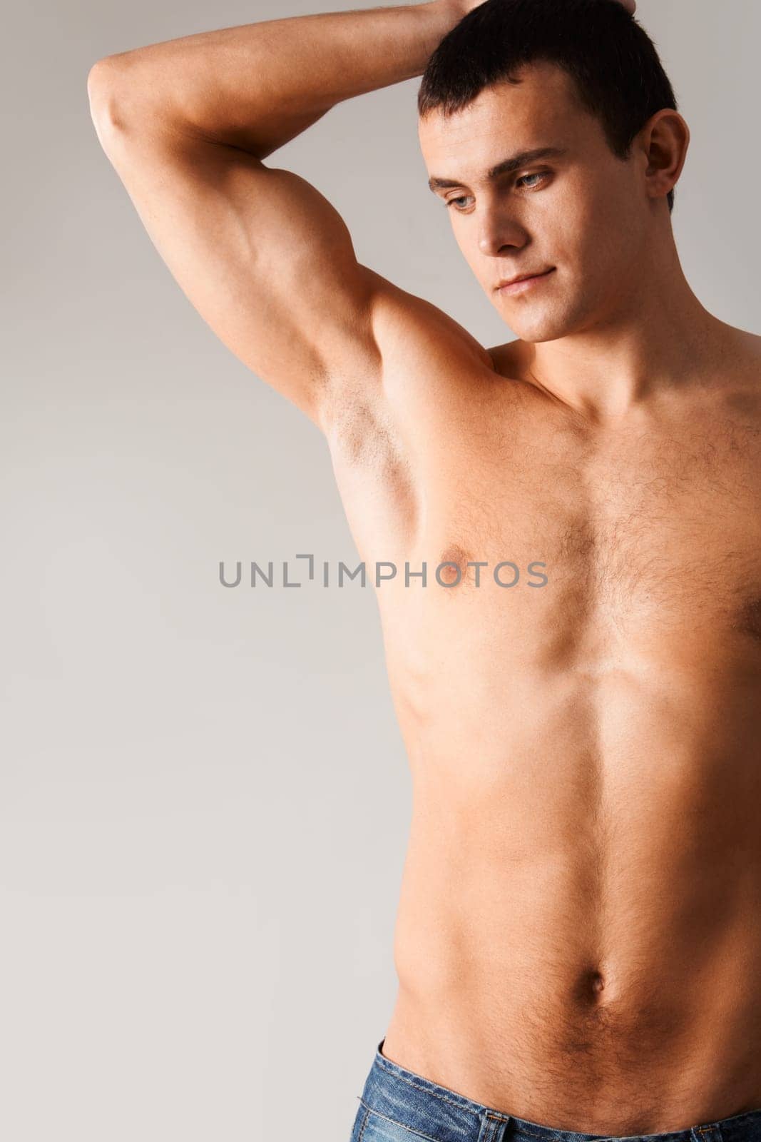 Image of shirtless man in jeans isolated over grey background