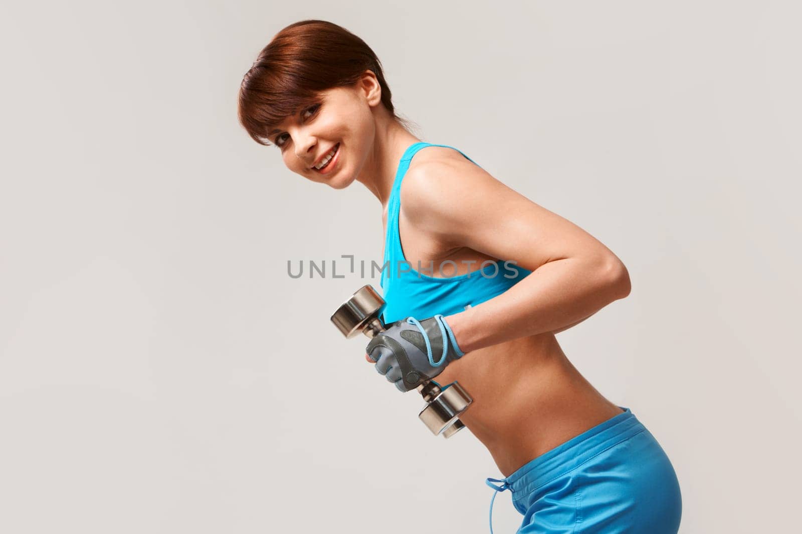 Image of smiling woman with barbells in hands looking at camera