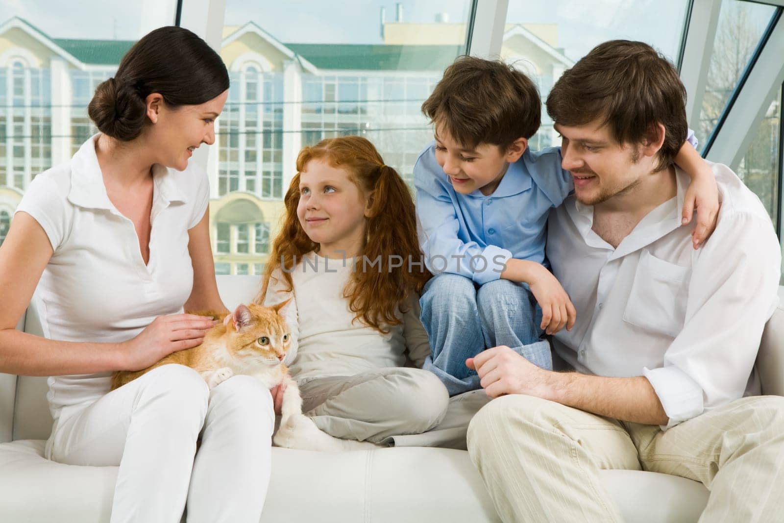 Portrait of careful parents and their two children enjoying weekend day at home