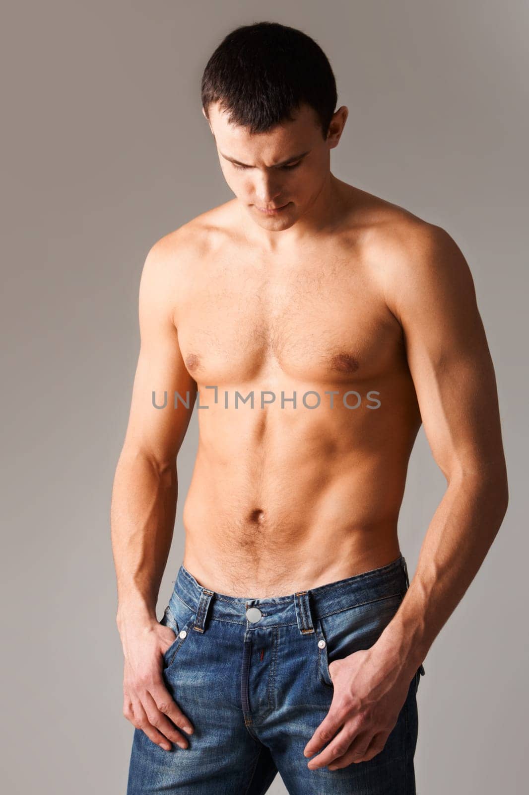 Image of shirtless man in jeans isolated over grey background