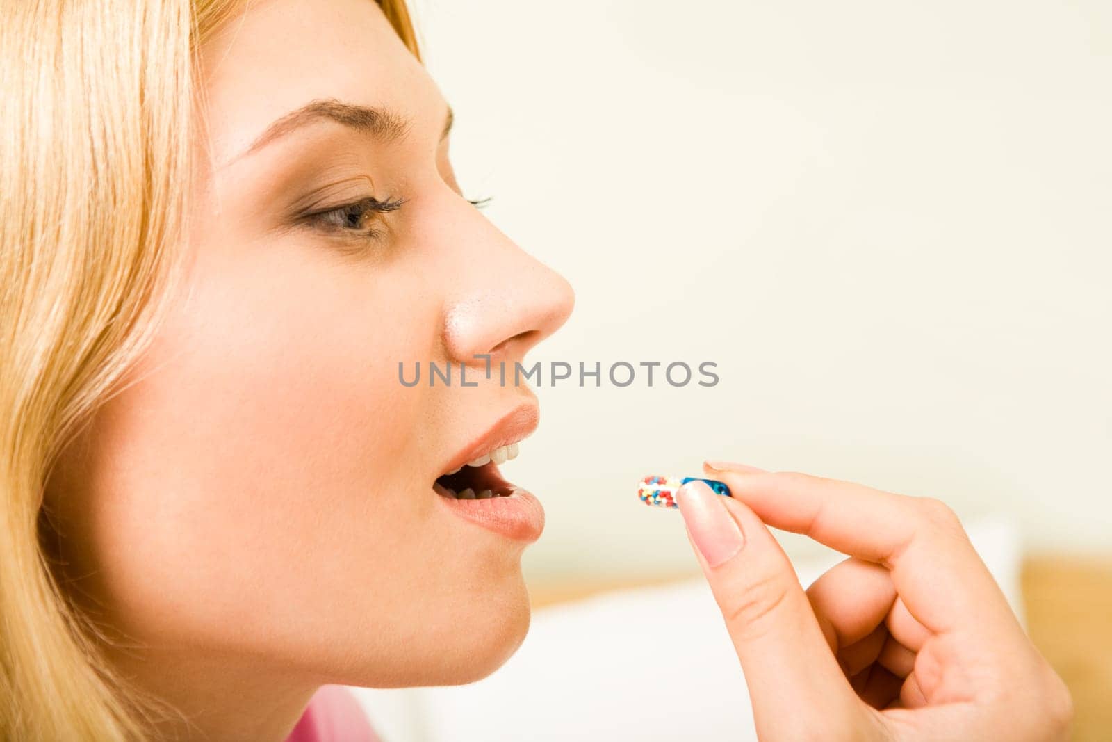 Profile of young woman holding pill by her mouth before taking it