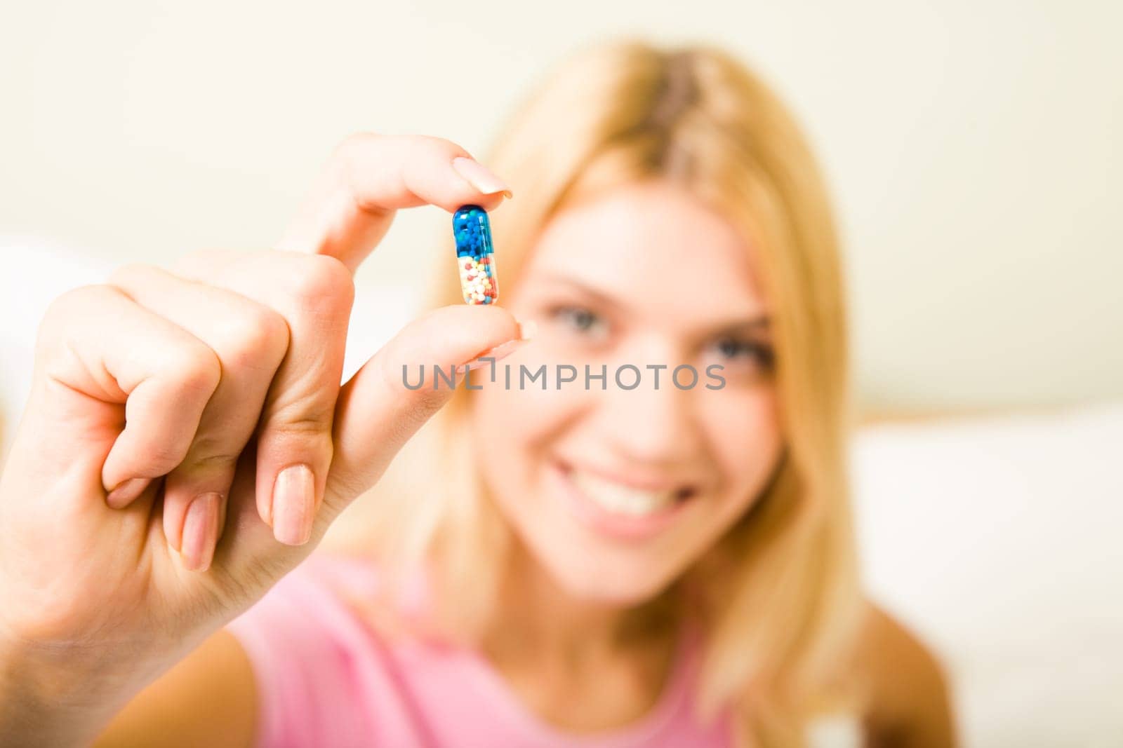 Close-up of womans hand holding pill between thumb and forefinger