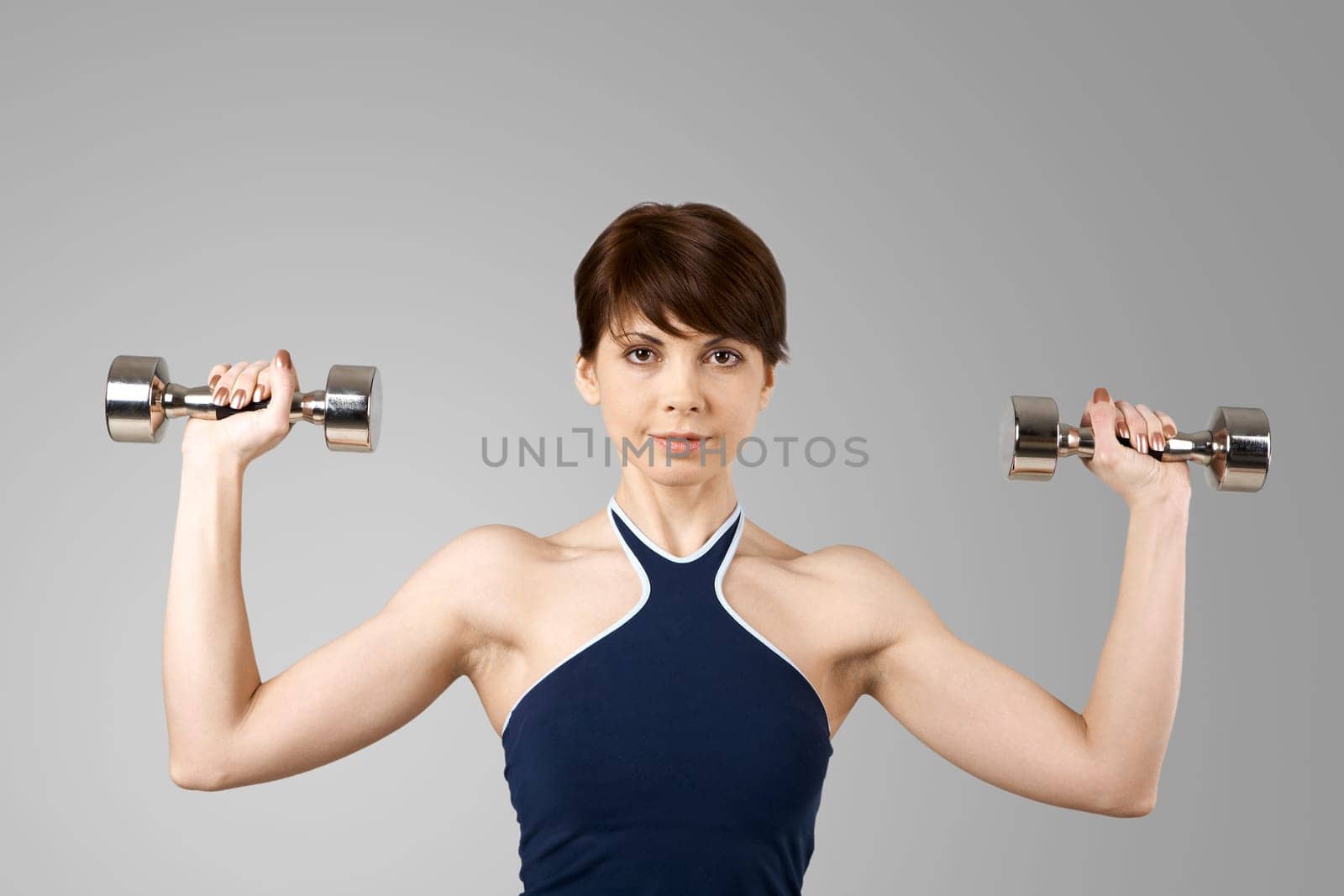 Image of smiling woman exercising with barbells in hands