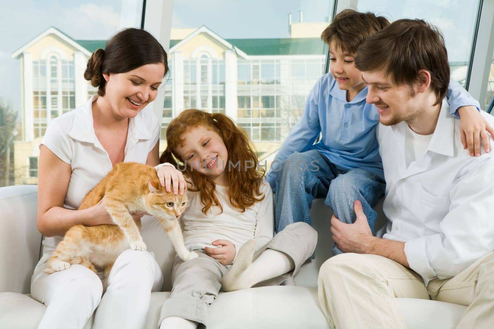 Photo of cute girl caressing pet on her mothers knees while father and boy looking at it