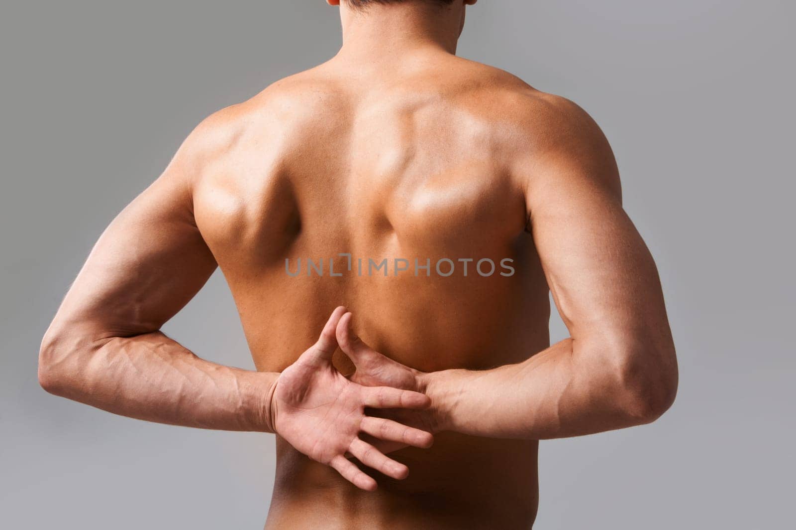 Back view of shirtless man keeping his hands behind back