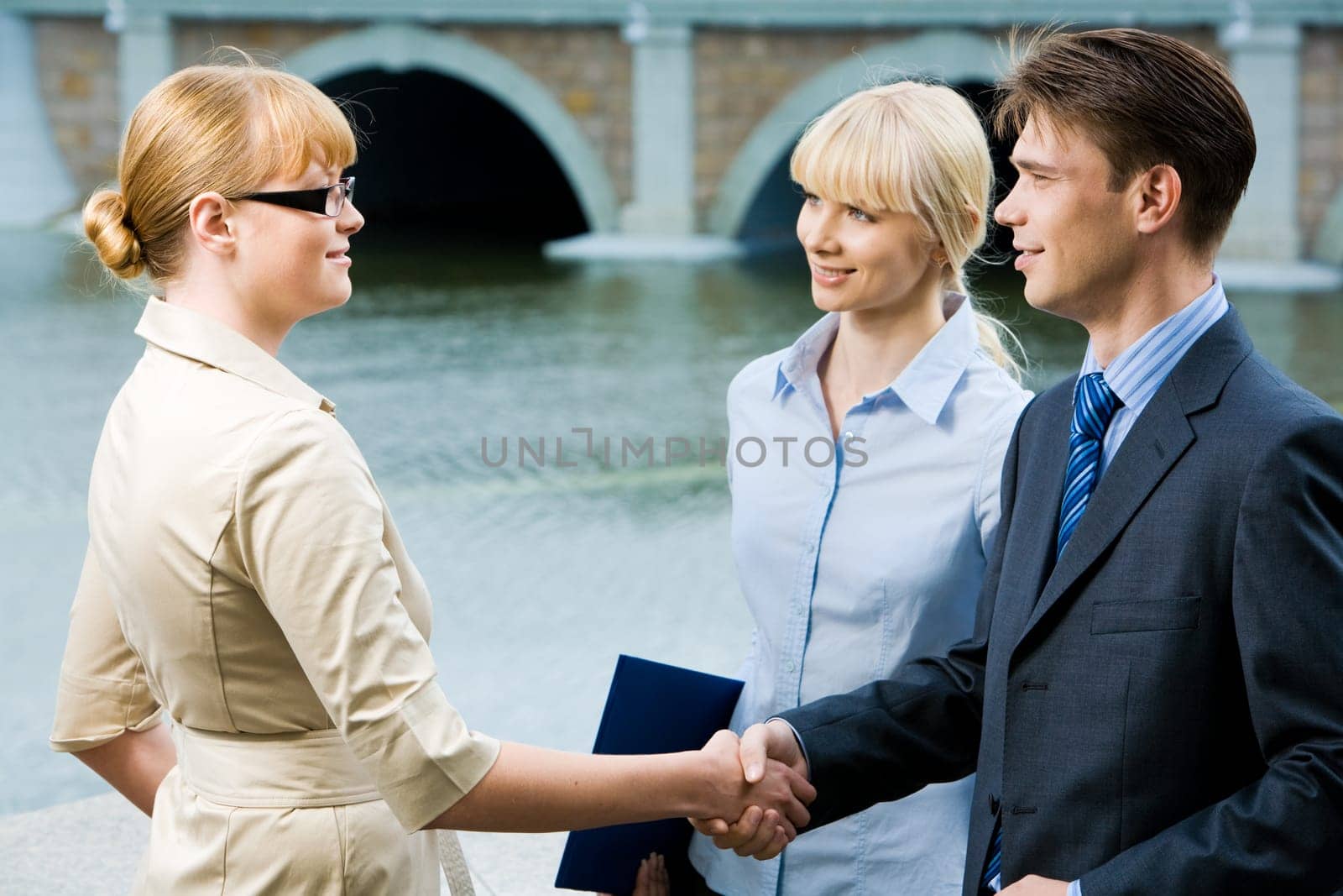 Portrait of business partners handshaking at meeting and looking at each other