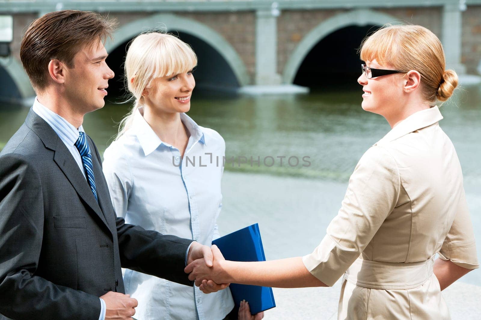 Portrait of business partners handshaking at meeting and looking at each other