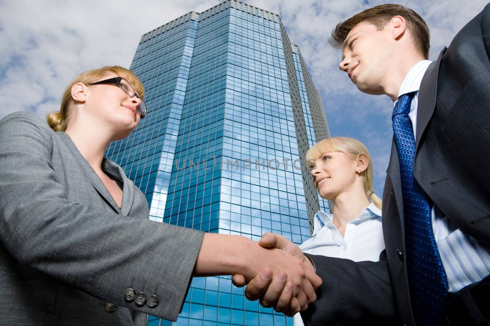 View from below of successful businesspeople handshaking as symbol of collaboration