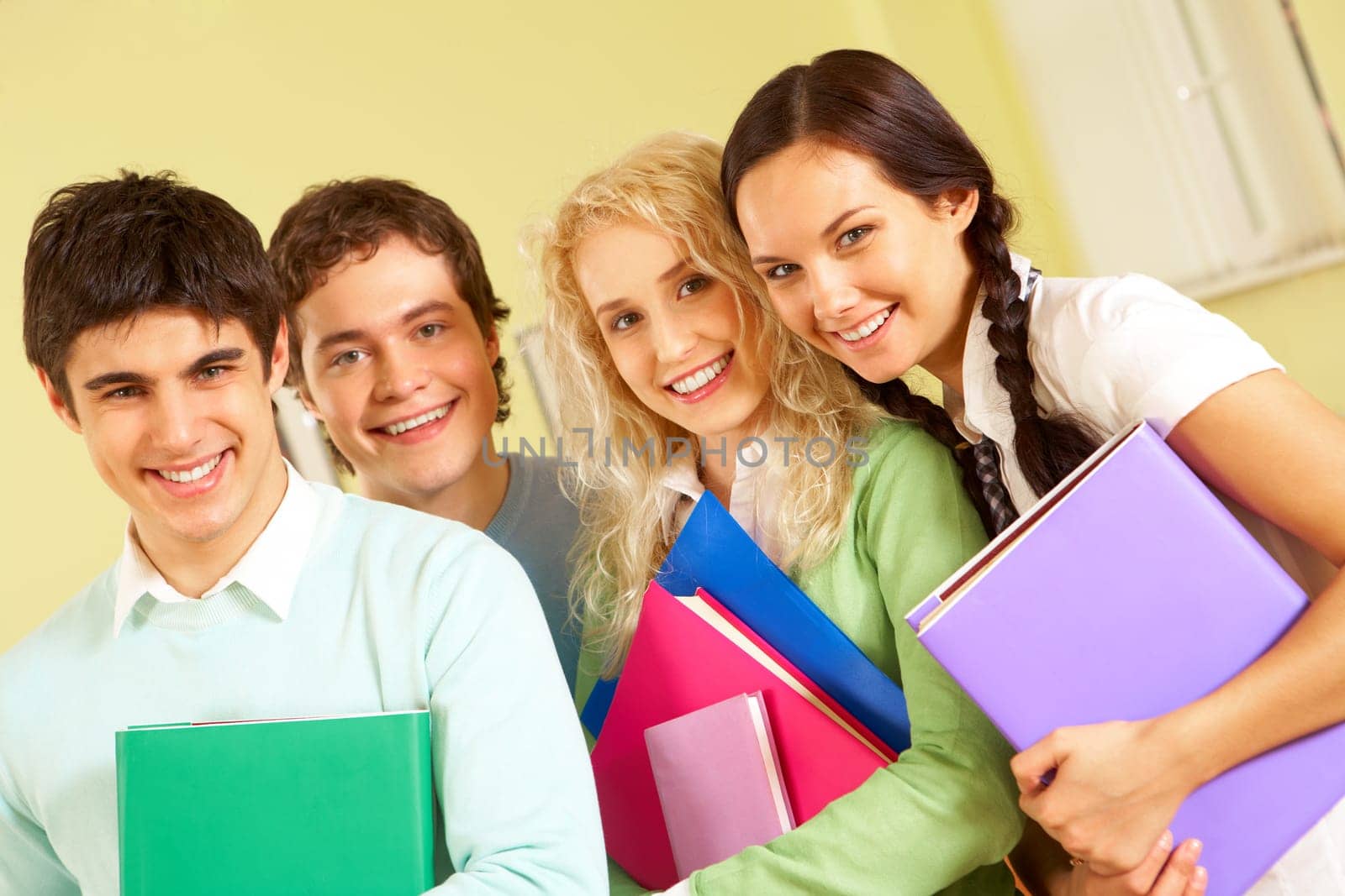 Portrait of happy students standing close to each other and looking at camera with smiles