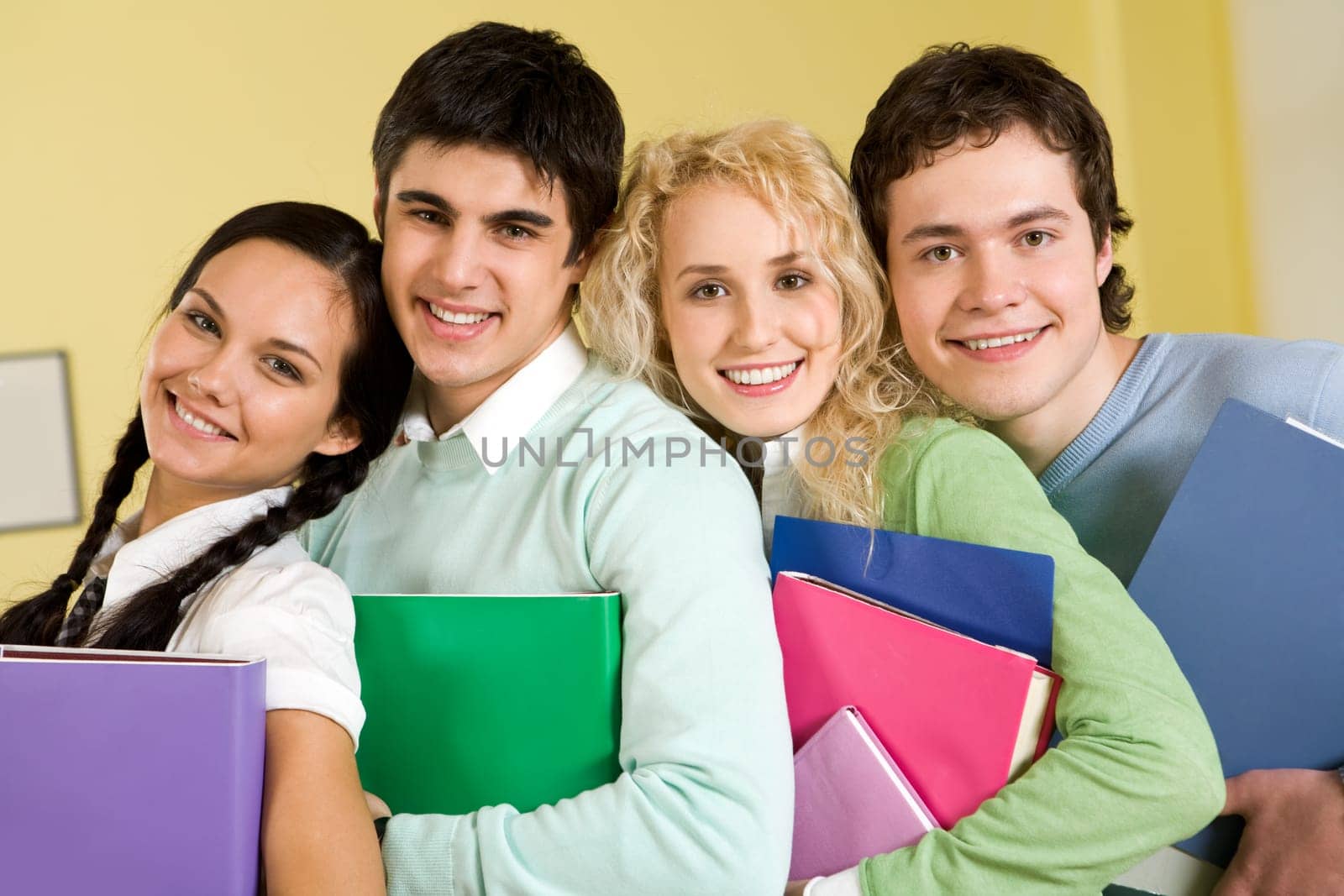 Portrait of happy students standing close to each other and looking at camera with smiles