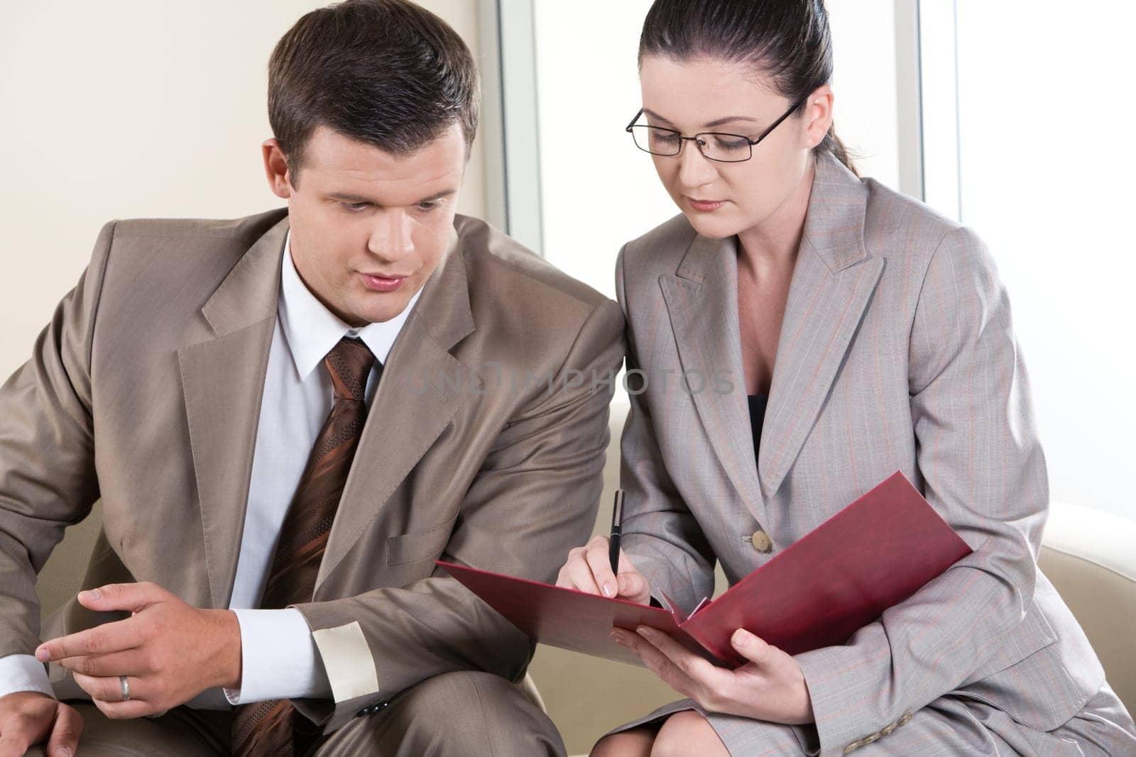 Portrait of businessman and lady communicating while looking at document in the office