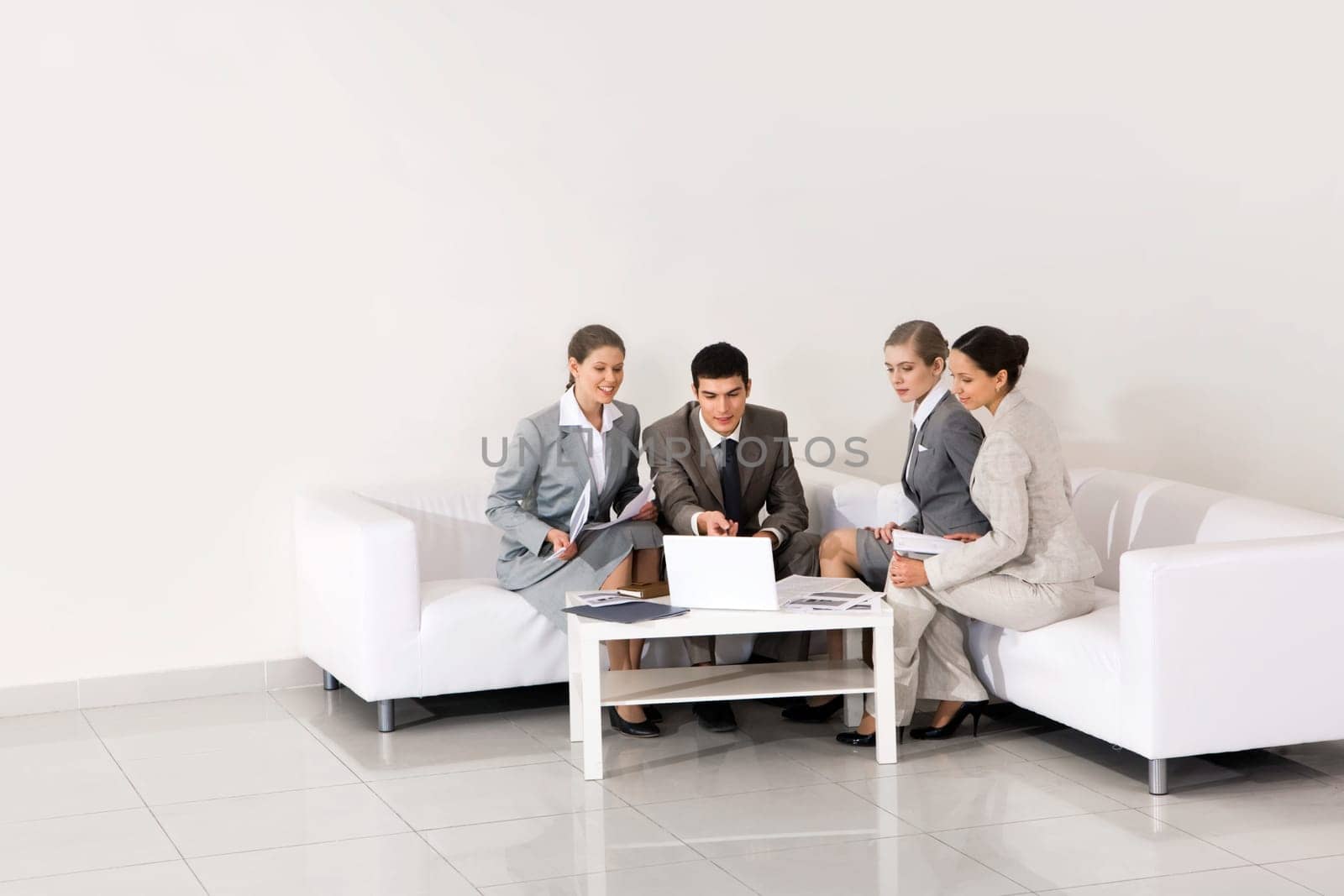 Portrait of friendly workteam looking at laptop monitor being pointed at by smart employer