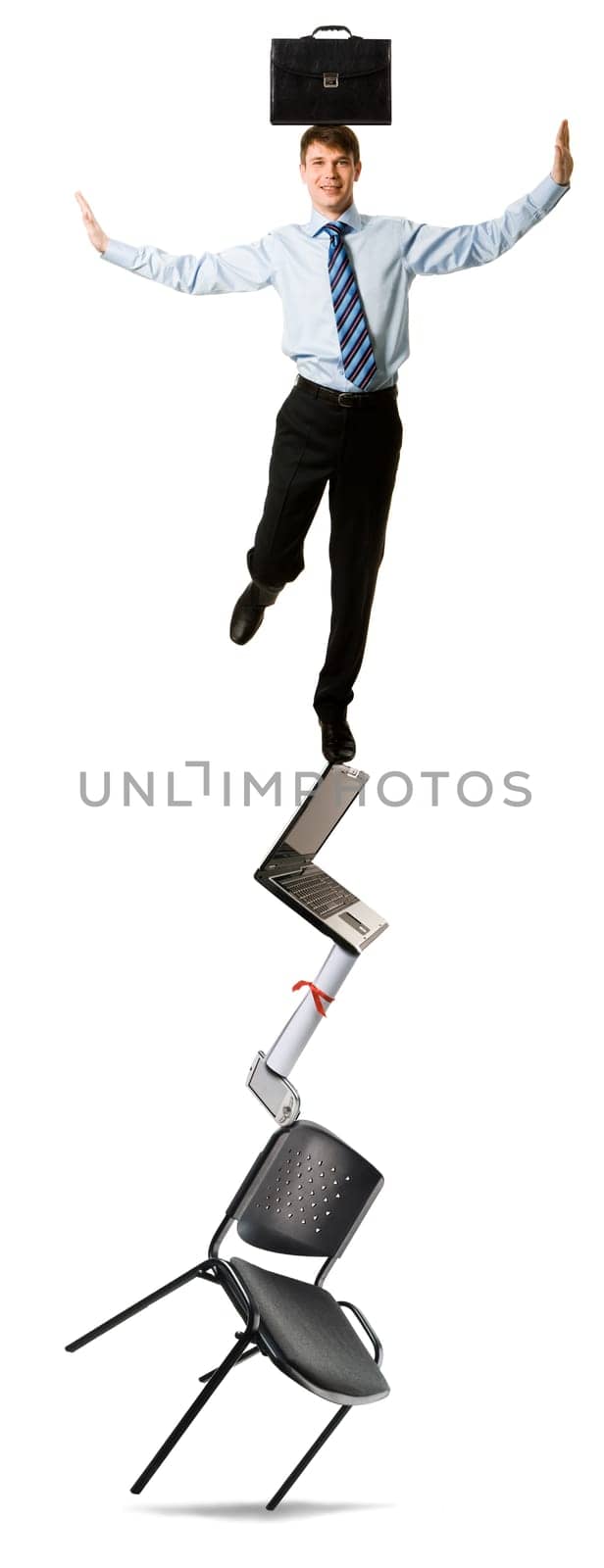 Image of successful businessman with briefcase standing on top of pile of business objects