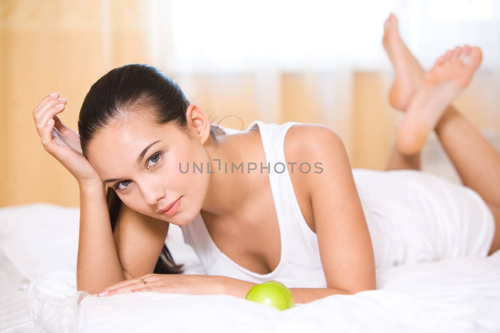 Portrait of brunette lying in bed and looking at camera with smile