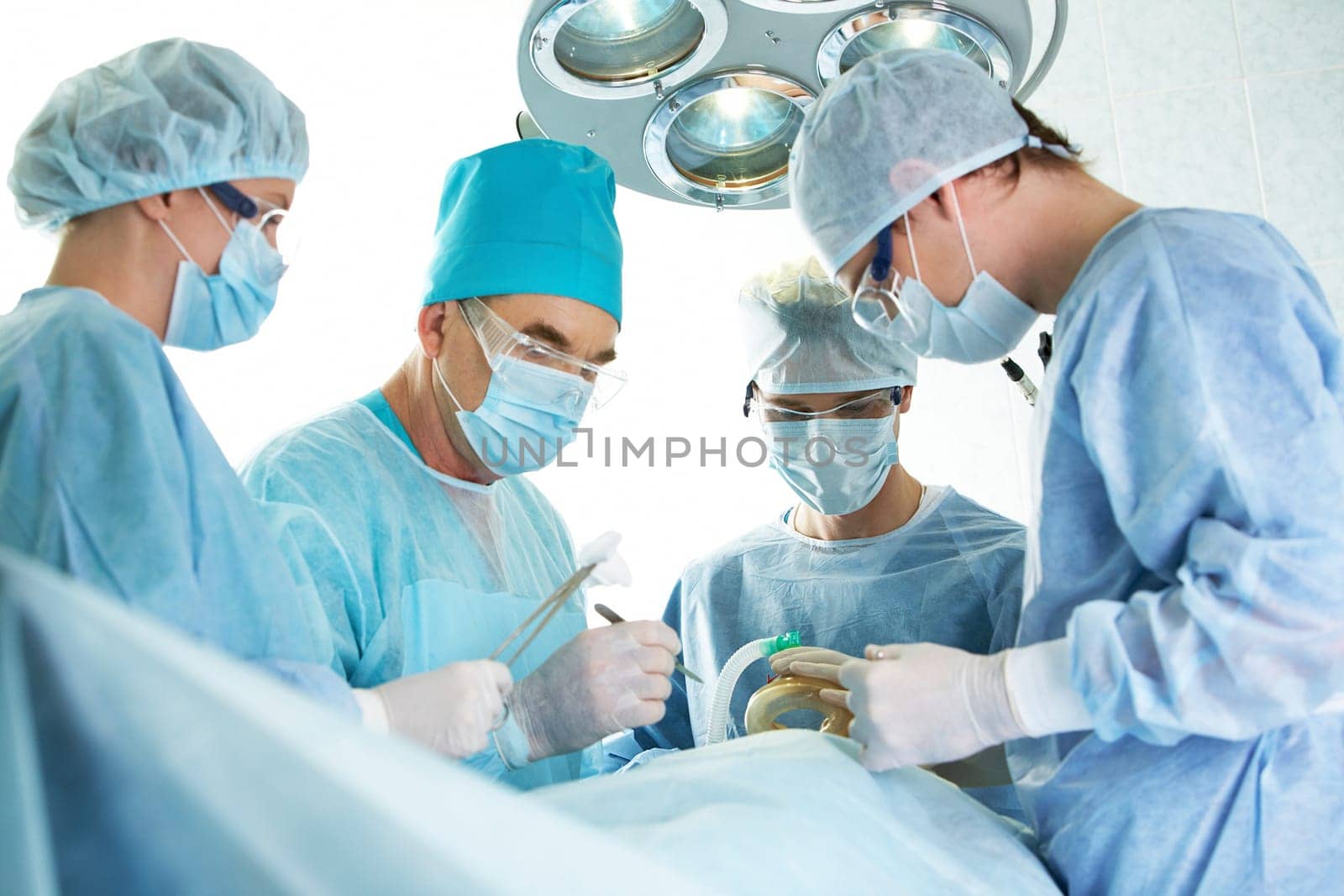 Several surgeons surrounding patient on operation table during their work