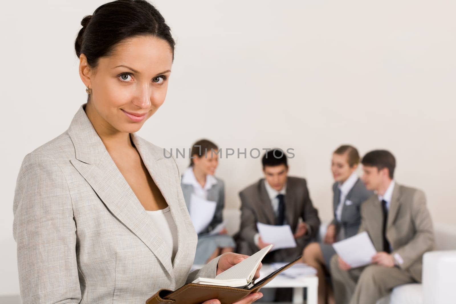 Portrait of smart businesswoman looking at camera on background of working colleagues