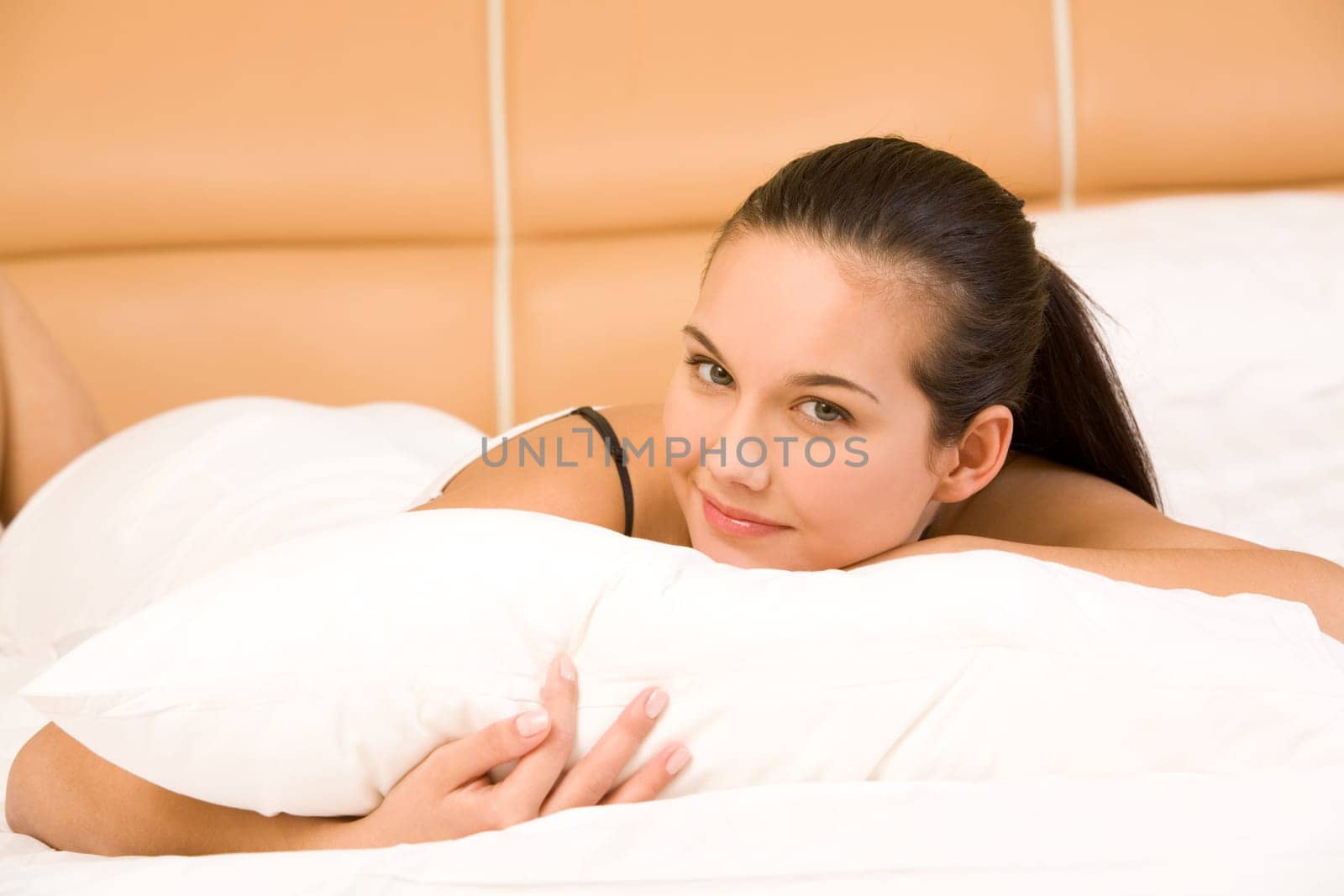 Portrait of brunette lying in bed and looking at camera