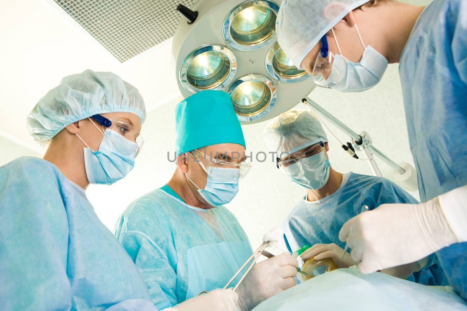 Group of surgeons looking at patient on operation table during their work