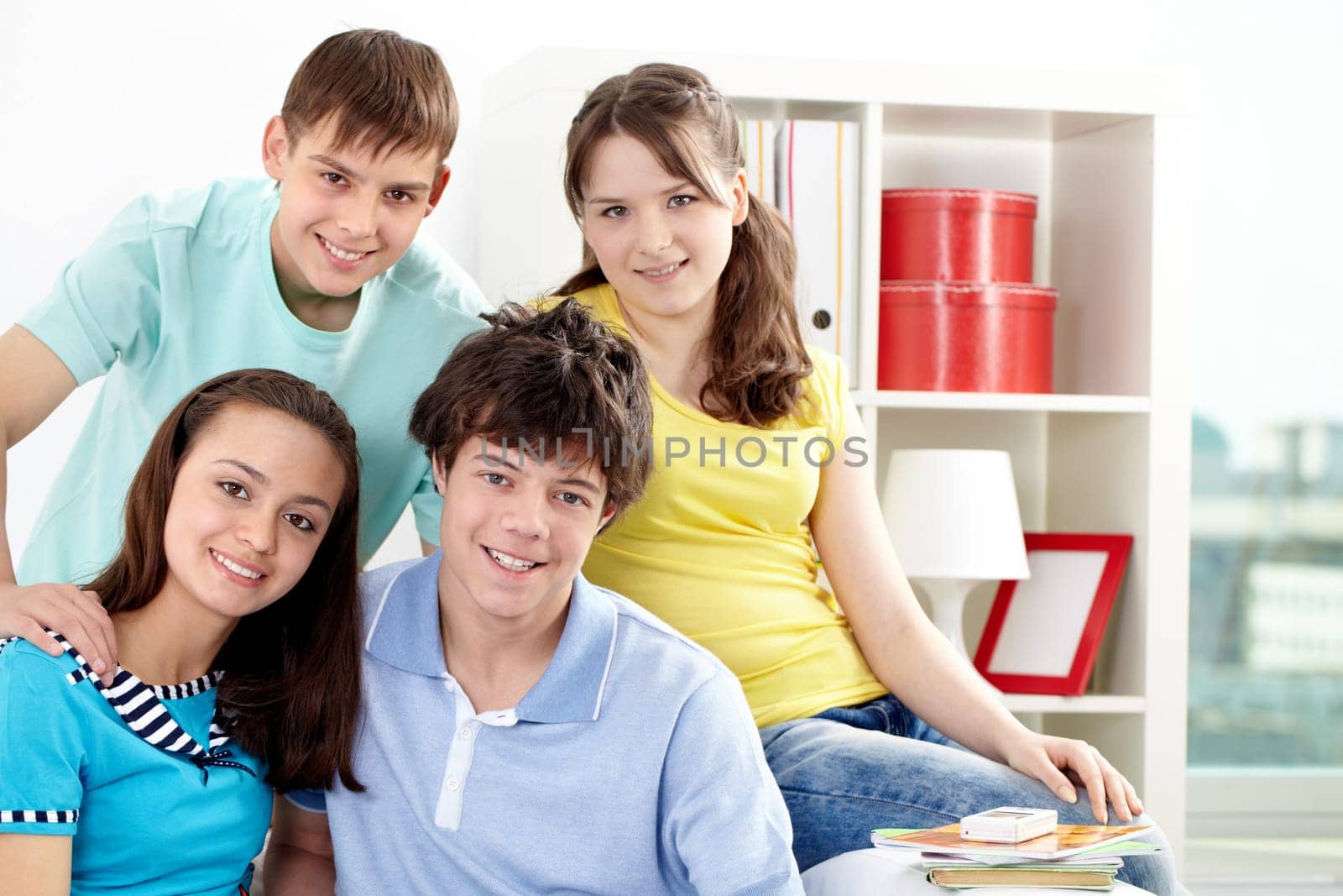 Portrait of four friends sitting together, looking at camera and smiling
