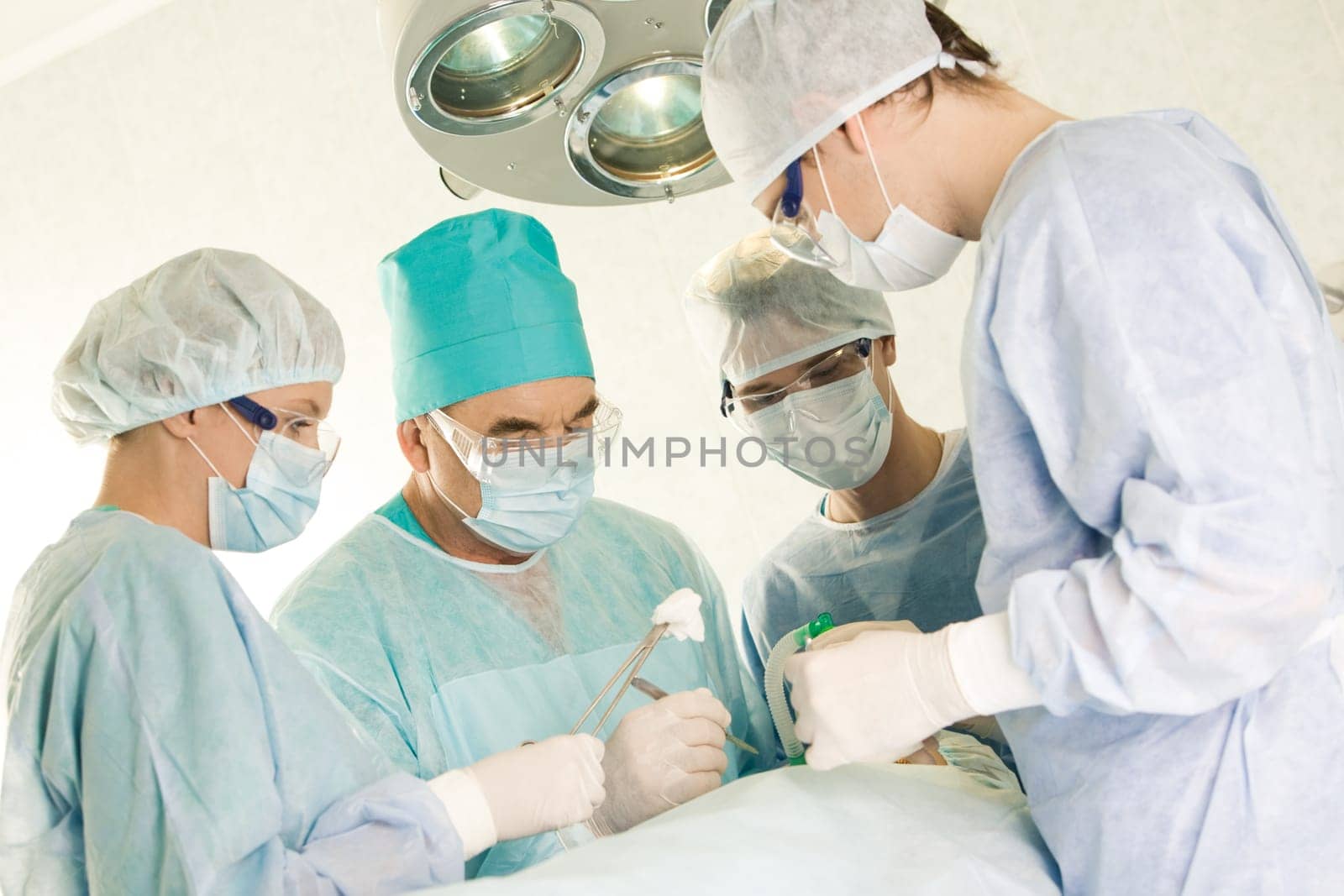 Several surgeons surrounding patient on operation table during their work