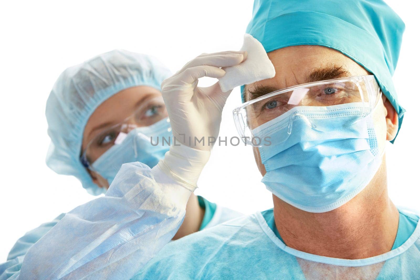 Image of surgeon during work with his forehead being rubbed by nurse