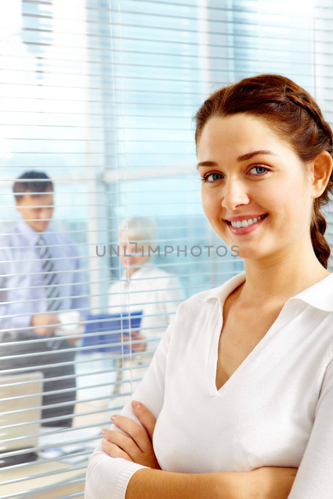 Female leader looking at camera on background of team of partners working in office